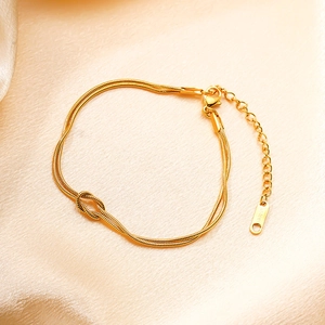 Bracelet double chaîne serpent dorée avec design à nœud sur soie champagne