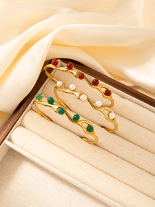 Detailed view of wave-shaped 18k gold plated bangles with pearls and gemstones