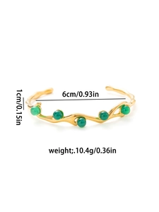 Detail of 18K gold-plated C-shape bracelet with wave texture and green gemstones