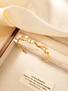 Detailed view of gold wave-shaped bangle with five pearls set in a premium jewelry box