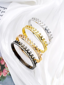 Macro shot of crown bangles in four finishes with zircon crystals and silk background