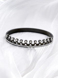 Detail of black crown bangle in titanium steel with pave-set sparkling zircons