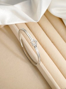 Vue macro d'un bracelet jonc étoile en argent avec zircons sur coffret en velours