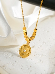 Détail de pendentif soleil doré avec perle et perles carrées en métal sur le collier