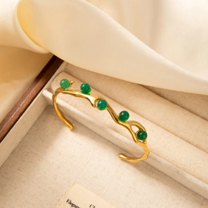 18k gold plated stainless steel open bangle with five green gemstones in a jewelry box