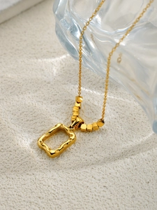 Détail du pendentif soleil doré avec texture ondulée irrégulière sur cadre carré évidé