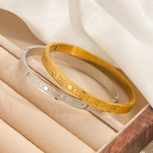 Close-up of gold and silver sun and moon engraved bangles in a velvet jewelry box