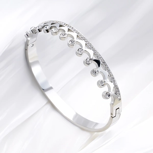 Elegant crown-shaped titanium steel bracelet with sparkling zircons on white silk background
