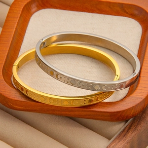Close-up of gold and silver sun moon bracelets with celestial reliefs in a wooden tray