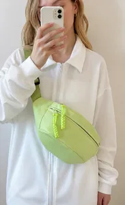 Detail van lichtgroene nylon borsttas met gele ritstrekker gedragen door model