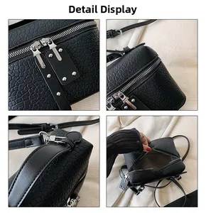 Detail view of black stone texture crossbody bag with silver zippers and metal rivets
