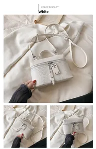 Detail of white crocodile pattern shoulder bag with top zipper and slim strap