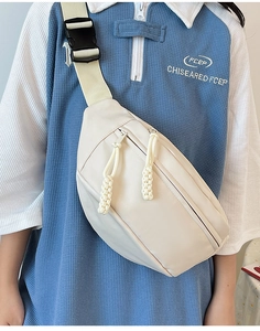 Gros plan d'un sac bandoulière beige avec cordons de fermeture et boucle en plastique
