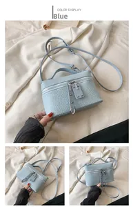 Detail of light blue croc-embossed handbag with buckle strap and top handle design