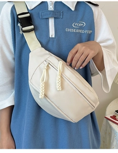 Détail du sac bandoulière blanc cassé avec sangle tissée et boucle porté par le mannequin