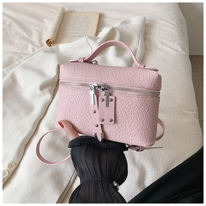 Detailed macro view of the pink embossed leather texture and silver zipper of this handbag