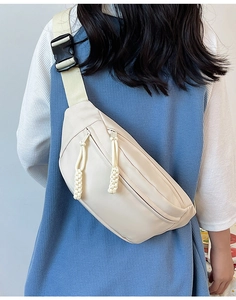 Détail du sac bandoulière blanc crème minimaliste avec large sangle porté par un mannequin