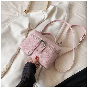 Detailed view of a pink box bag featuring embossed croc texture and silver metal studs