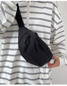 Détail d'un sac bandoulière noir minimaliste avec tirette tissée et sangle réglable