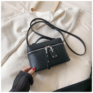 Detail of black box crossbody bag featuring lychee grain texture and silver zippers