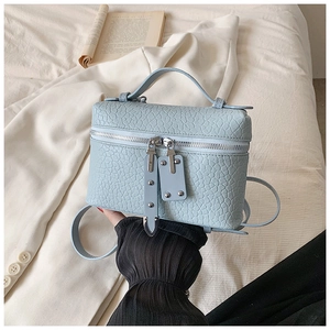 Close-up of light blue crocodile embossed leather handbag with silver double zippers