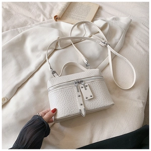 Detailed shot of white faux-crocodile leather handbag with silver metallic zippers