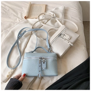 Detail of light blue crocodile embossed square handbag with metallic studs and zipper