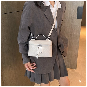 Detail of off-white lychee leather texture and dual zipper on crossbody square bag