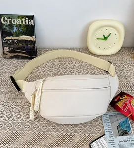 Detailopname van de crème canvas borsttas met geweven ritsrekkers op een kanten achtergrond