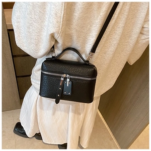 Detail of black pebble grain leather square bag with top handle and detachable strap