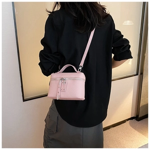 Pink mini vanity case handbag with pebble leather texture and crossbody strap shown on model