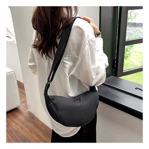 Detailed view of black nylon crescent bag worn crossbody over a white shirt