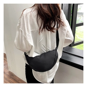 Close-up of black nylon crescent bag with adjustable wide strap on a white shirt