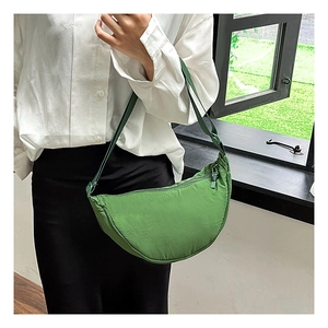 Detail of a bright green nylon crescent bag with adjustable strap worn by a model