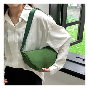 Green nylon crescent dumpling bag with adjustable shoulder strap worn by female model