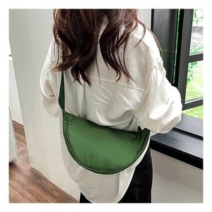 Rear view of model wearing a green nylon half-moon crossbody bag with wide shoulder strap
