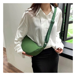 Detail view of a stylish green nylon crescent bag worn crossbody by a female model