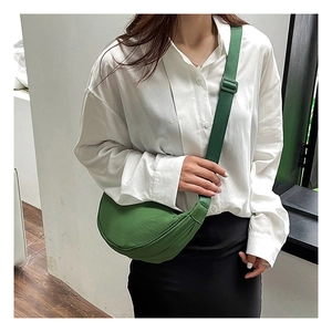 Detailed view of grass green crescent nylon bag worn by a model in minimalist style