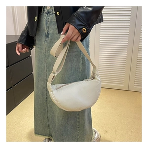 Side view of white nylon crescent bag with adjustable wide strap on female model