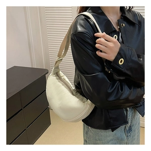 Detail of cream nylon crescent bag with adjustable shoulder strap worn by a model