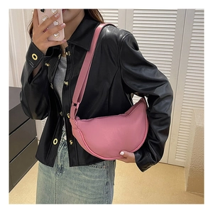 Close-up of pink crescent nylon shoulder bag worn over a black leather jacket