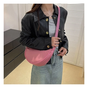 Pink nylon crescent crossbody bag styled with a black jacket for a minimalist look