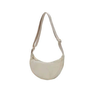 Detail view of the adjustable wide fabric strap and cream nylon crescent shoulder bag