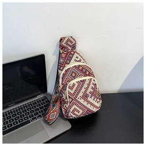 Ethnic woven chest bag with geometric patterns next to a laptop in a lifestyle setting