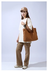 Brown canvas tote bag worn by a model, showcasing large capacity and casual urban style