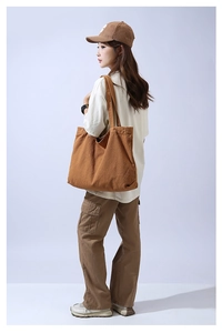 Side view of a large brown canvas tote bag on a model showing daily casual style