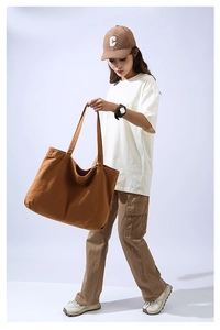 Brown canvas tote bag displayed by a model to show large capacity and casual style