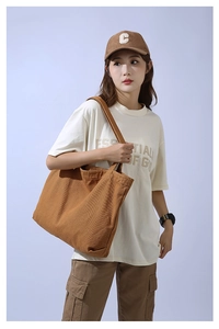 Brown canvas tote bag worn by a model, showing the large capacity and durable material