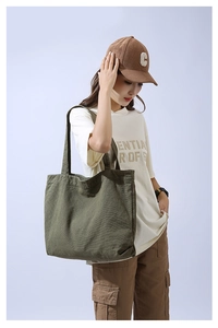 Detail of olive green canvas tote bag showing its large capacity on a female model