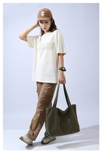 Full body shot of a model carrying a large olive green canvas tote bag with casual outfit